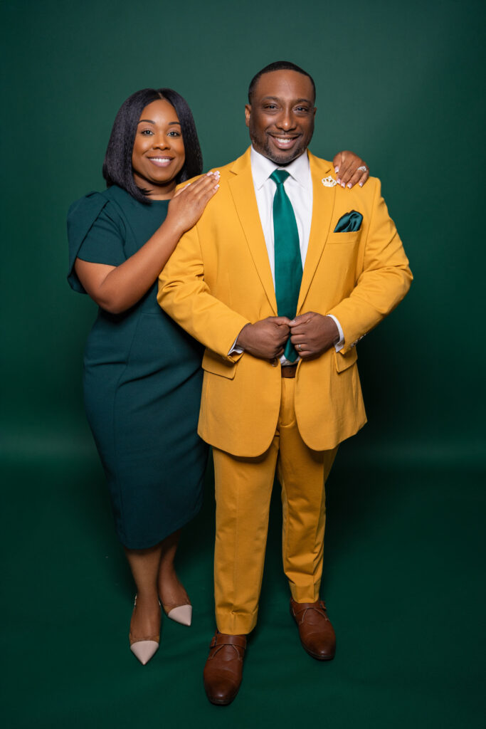 A stylish couple poses against a green backdrop, dressed elegantly in green and yellow.