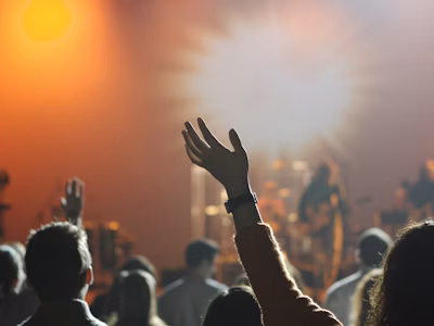 Raised hands at a lively concert with warm lighting.